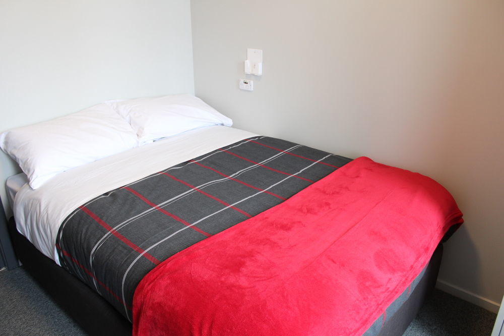 Urbanz Hostel Christchurch Buitenkant foto A bed with a throw